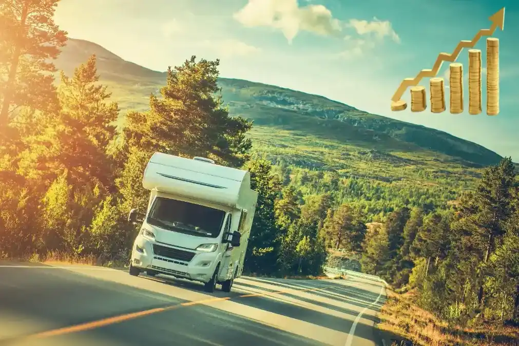 Ein Wohnmobil fährt auf einer kurvenreichen Straße durch eine grüne Landschaft mit Bäumen und Bergen im Hintergrund.